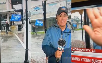 Triggered Weatherman Covers Camera as Man with Massive Trump Flag Runs in Background During Hurricane Broadcast