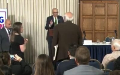 WATCH: “Please Sit Down!” – Schumer’s Anti Trump Speech Interrupted by Liberal Heckler Screaming, “How Dare You Talk About Corruption… Genocidal Maniac. Shame!”